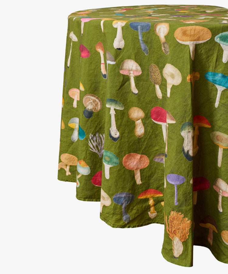 The John Derian Fungi Round Tablecloth features colorful illustrations of various mushrooms on avocado linen, offering a charming botanical print that’s perfect for curiosity cabinet decor.