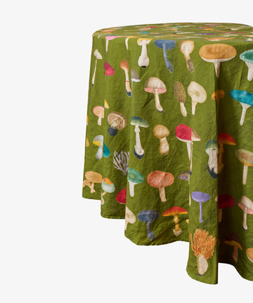 Elevate your space with the John Derian Fungi Round Tablecloth—a round, avocado linen tablecloth adorned with a vibrant botanical mushroom print on a crisp white background—ideal for introducing a touch of curiosity cabinet charm to your decor.