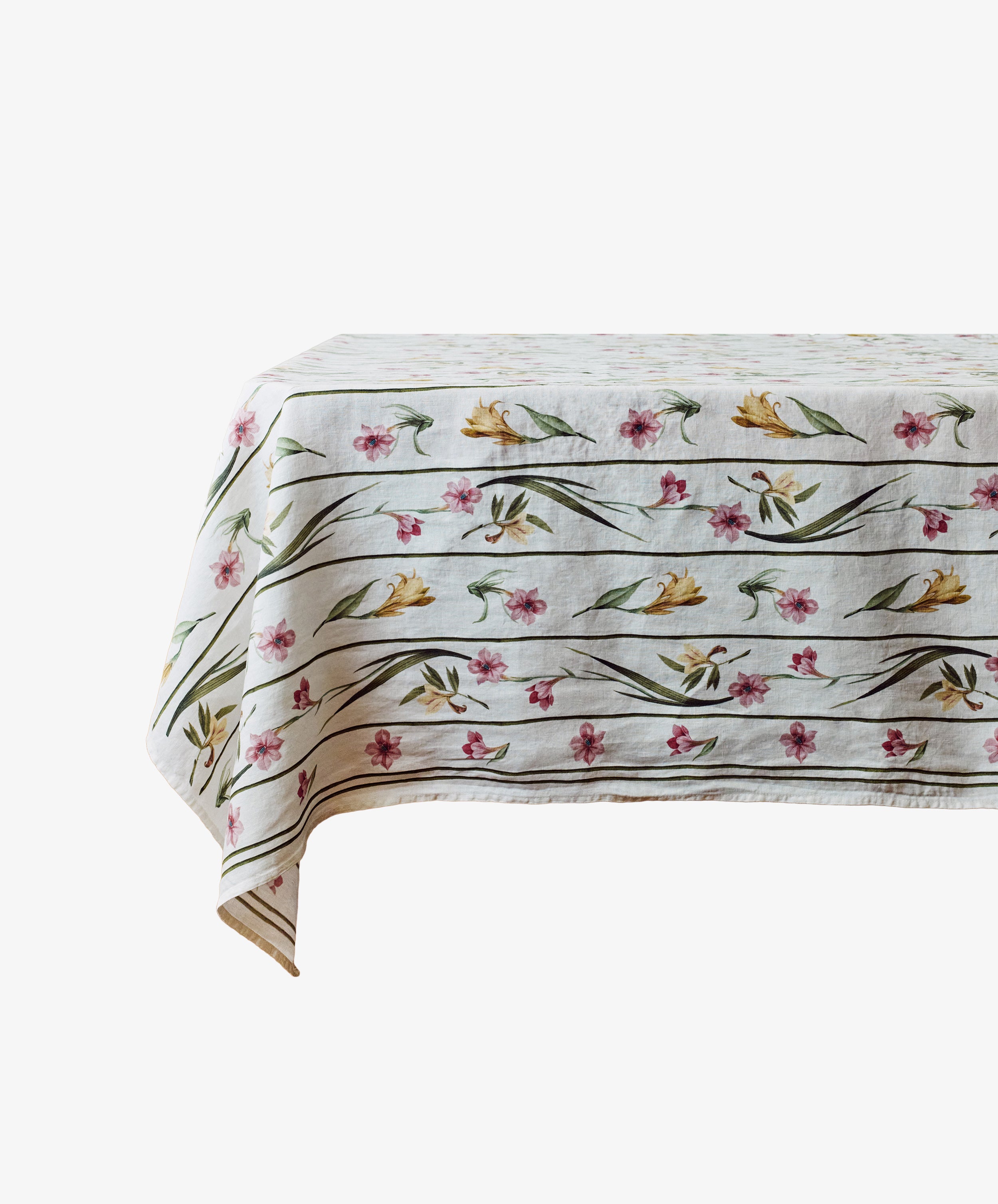 The Gladioli Tablecloth, featuring a white background with a floral pattern of yellow and pink flowers and green leaves, brightens your table decor.