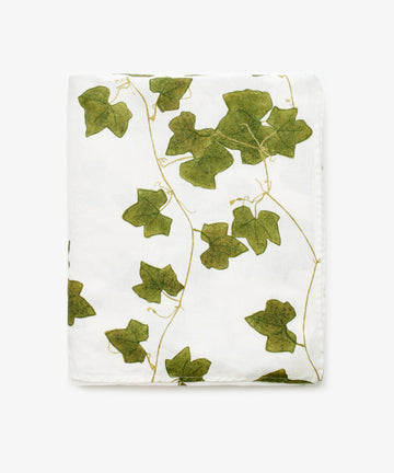 The Ivy Herbarium Linen Tablecloth, Medium, is a white linen tablecloth with a green ivy leaf and vine pattern inspired by nature.