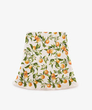 The L’Orangerie Round Linen Tablecloth features a vibrant orange fruit and green leaf pattern, reminiscent of classical French garden motifs, displayed against a crisp white background.