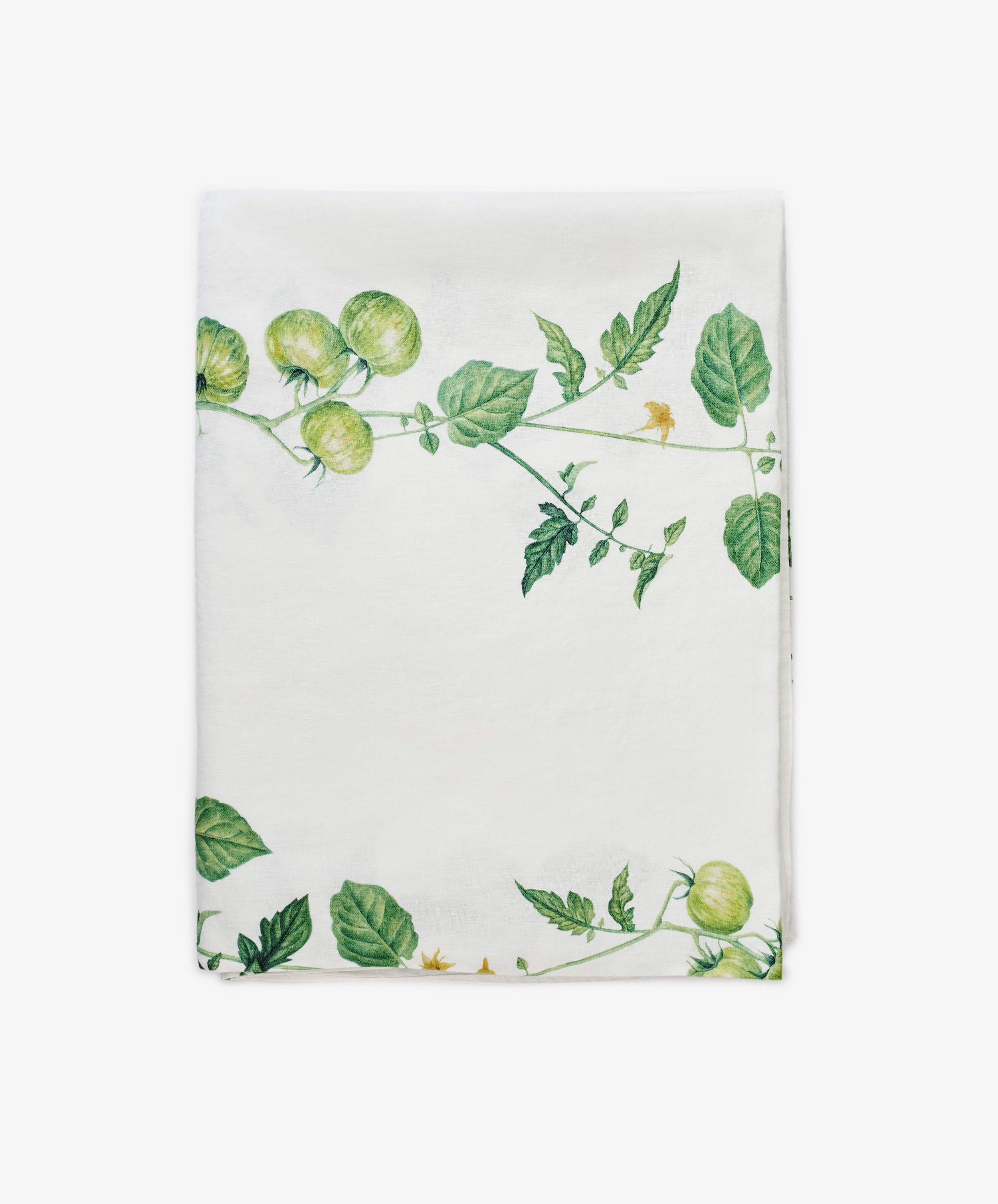 A white cloth napkin by Summerill & Bishop, featuring a Tomate Verte green tomato vine and leaf pattern along two edges, pairs beautifully with the matching Tomate Verte Linen Tablecloth.