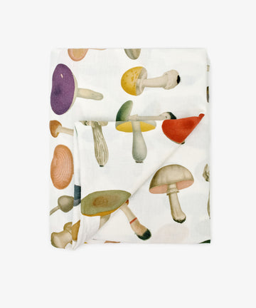 The John Derian Fungi Tablecloth is a white cloth adorned with a vibrant, vintage-inspired mushroom design printed across its surface.