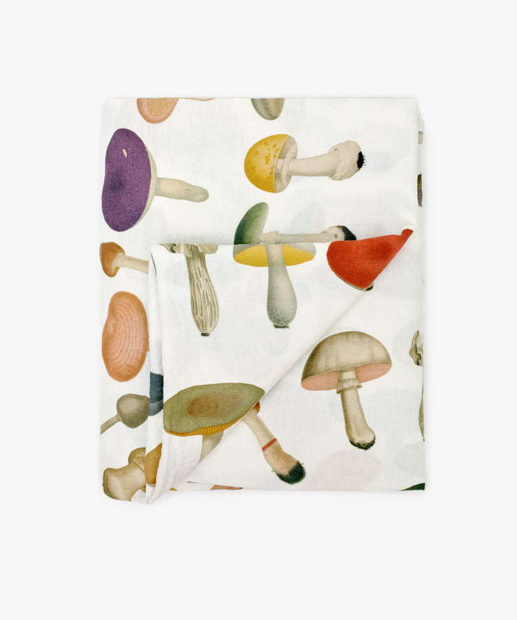 The John Derian Fungi Tablecloth is a white cloth adorned with a vibrant, vintage-inspired mushroom design printed across its surface.