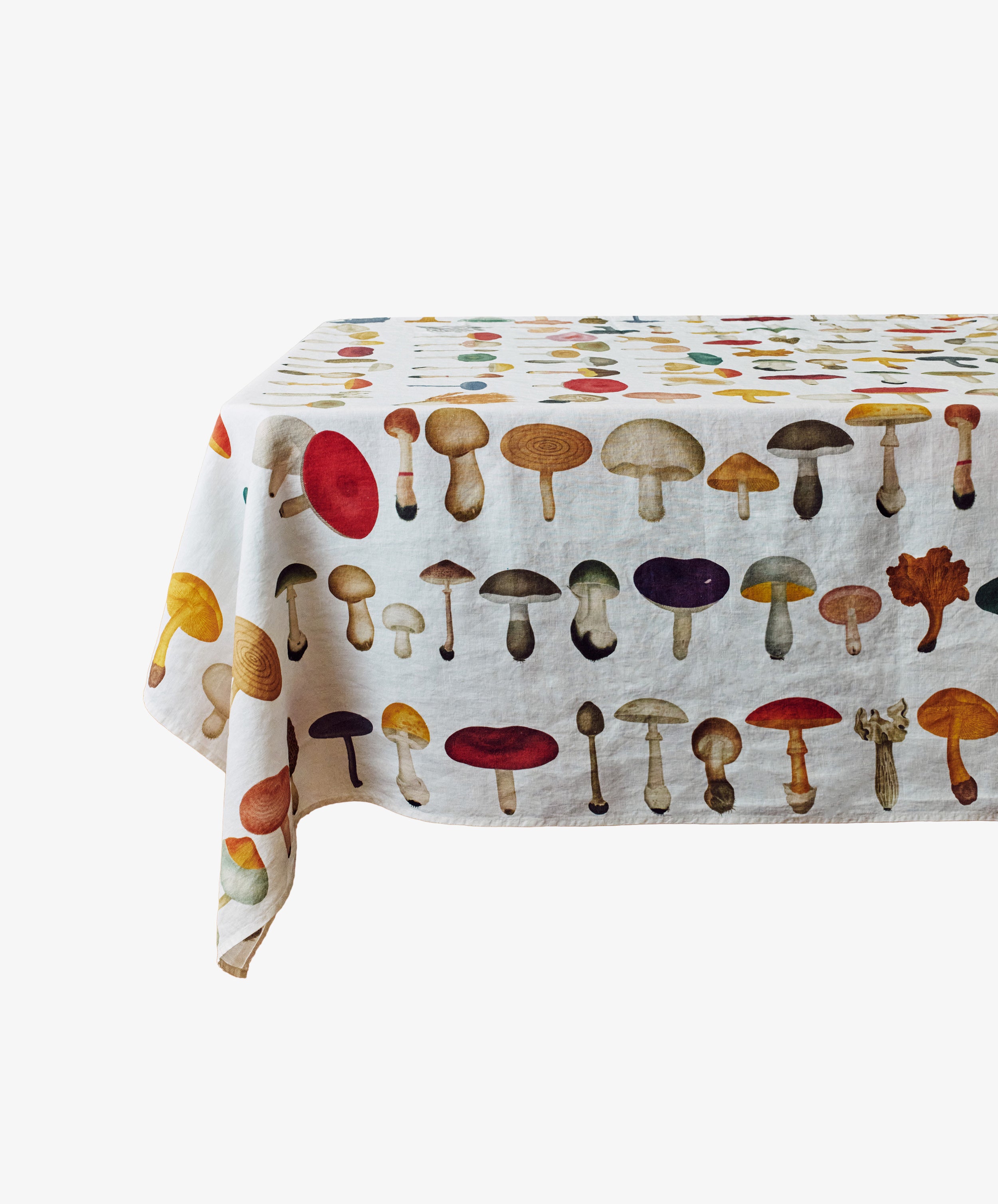 A rectangular table is covered with the John Derian Fungi Tablecloth, a white cloth featuring a colorful vintage-inspired mushroom design.
