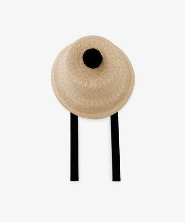 The Mount Hat is a beige handwoven straw hat featuring a black pom-pom on top and two black straps, shown against a plain white background.