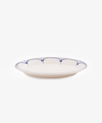 Side view of large Arco oval serving platter in white glazed ceramic with handpainted blue border design.