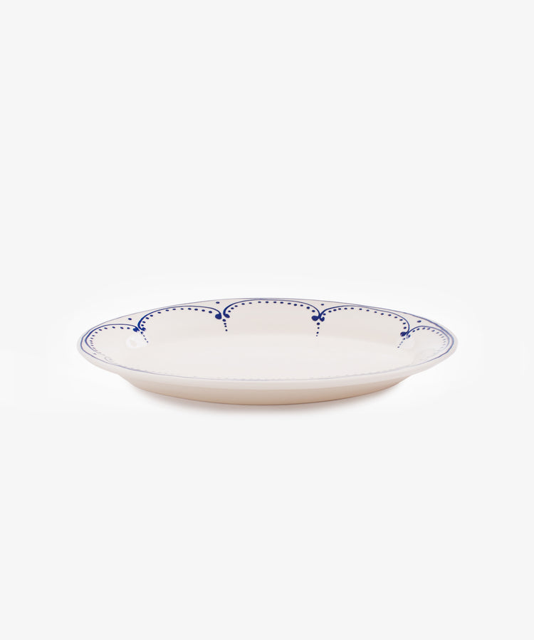 Side view of large Arco oval serving platter in white glazed ceramic with handpainted blue border design.