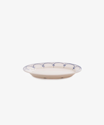 The Arco Oval Serving Platter features a shallow ceramic design with a white base and blue scalloped rim, inspired by traditional Portuguese patterns, shown against a plain white background.