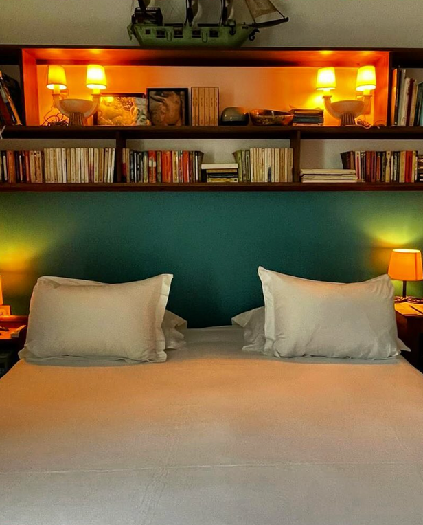 bed with two pillows and overhead bookshelf
