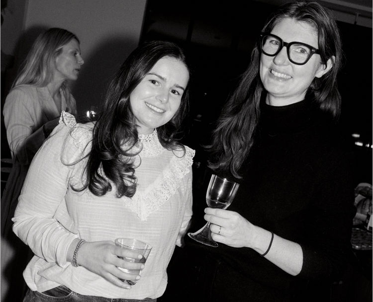 two woman holding drinks smiling at the camera