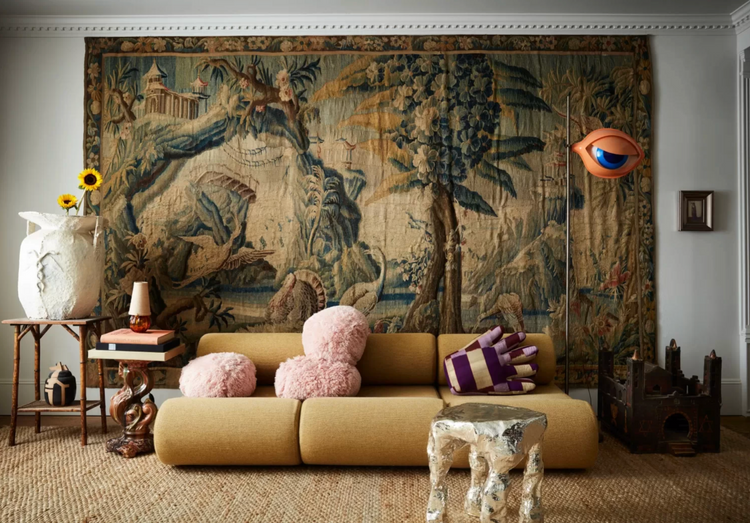 Living room with a large tapestry, beige sofa, and decorative items.