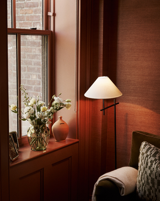 Nook with a window, vase of flowers, and lamp in a warm interior setting.