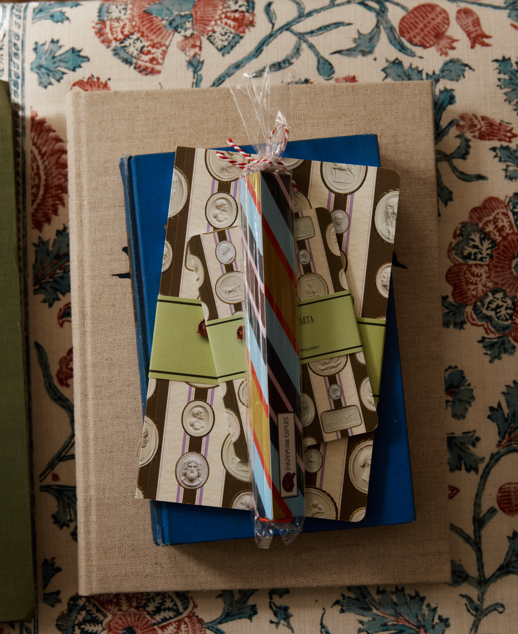 A Pencil Kit is stacked on top of a closed blue book, all placed on a floral-patterned surface.