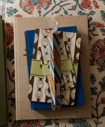 A Pencil Kit is stacked on top of a closed blue book, all placed on a floral-patterned surface.