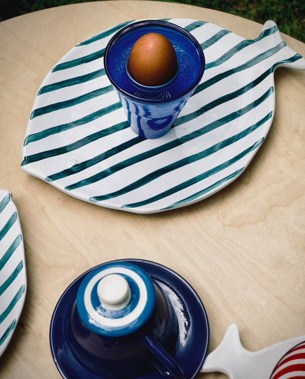 striped fish plate with egg inside of blue cup