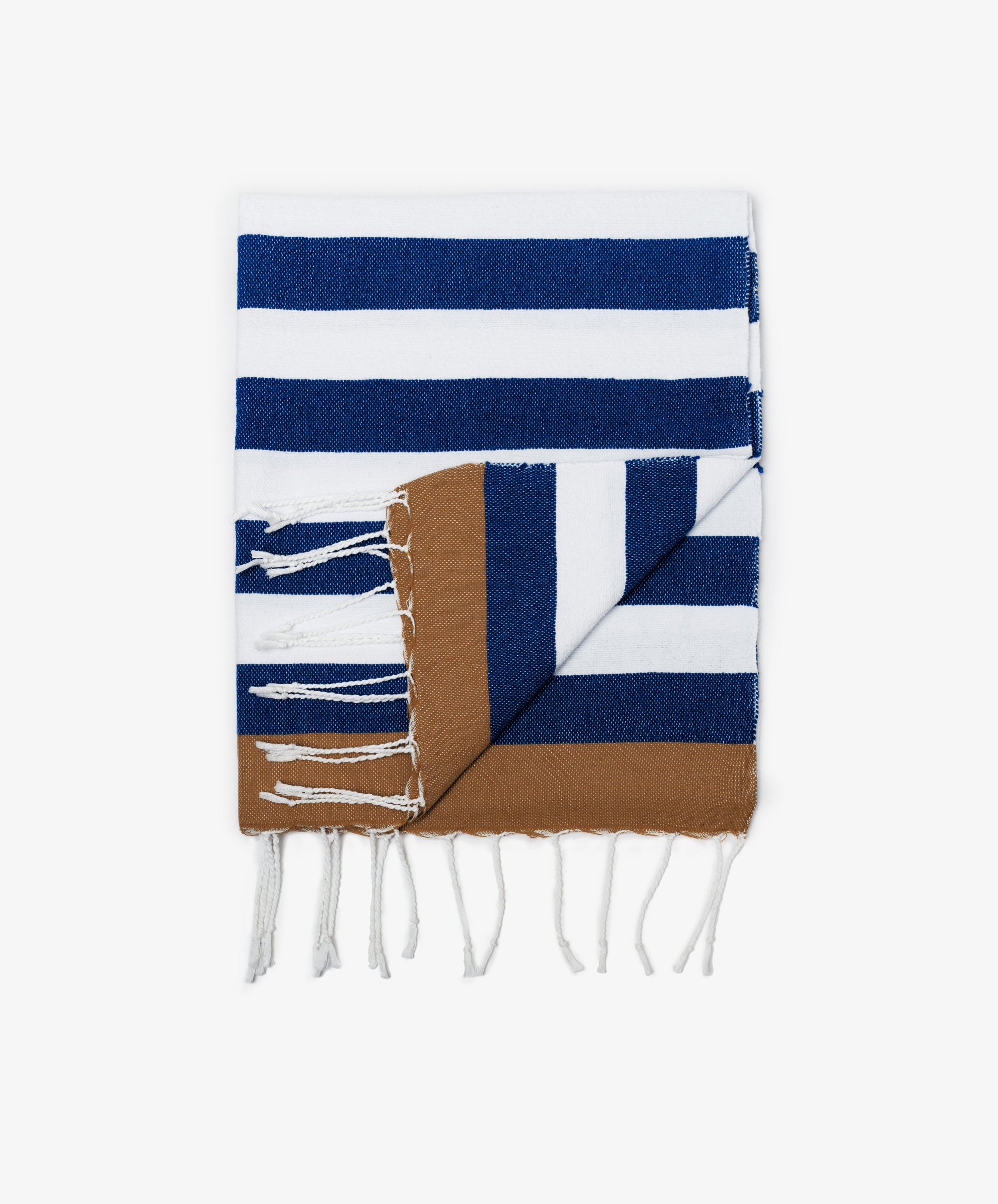 The La Plage Towel features wide blue and white stripes, a brown border, and white fringe on both ends. Lightweight and versatile, its perfect for travel or days at the shore.