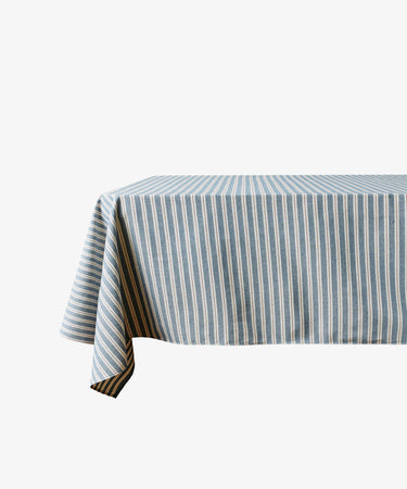 A rectangular table covered with the Martin Striped Tablecloth in blue and white is set against a plain white background.