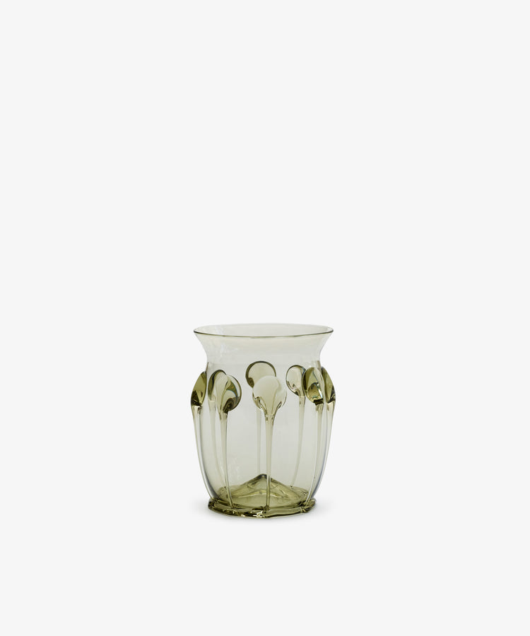 The Carlotta Vase is a translucent, mouth-blown piece with a pale green tint and raised vertical patterns along its sides, displayed against a plain white background.