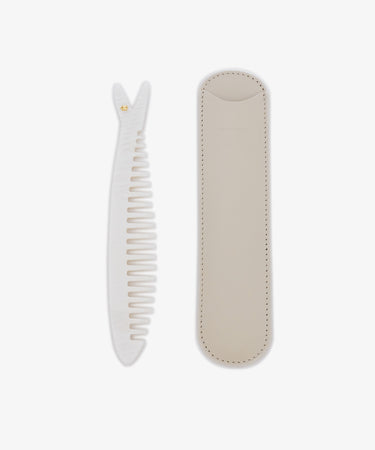 The Capri Sardine Comb, a white detangling comb with a textured handle, is shown beside its beige stitched leather protective case on a white background.