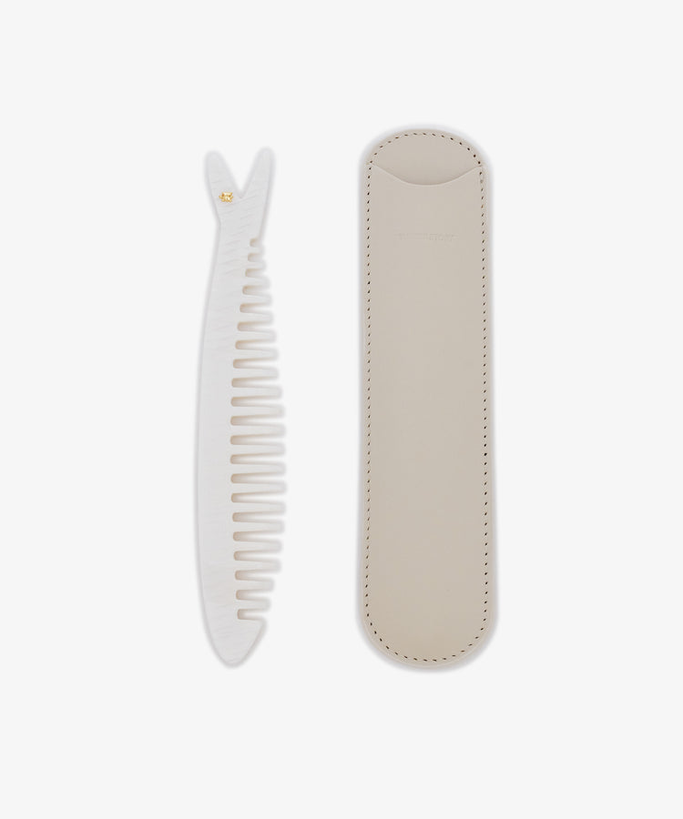 The Capri Sardine Comb, a white detangling comb with a textured handle, is shown beside its beige stitched leather protective case on a white background.