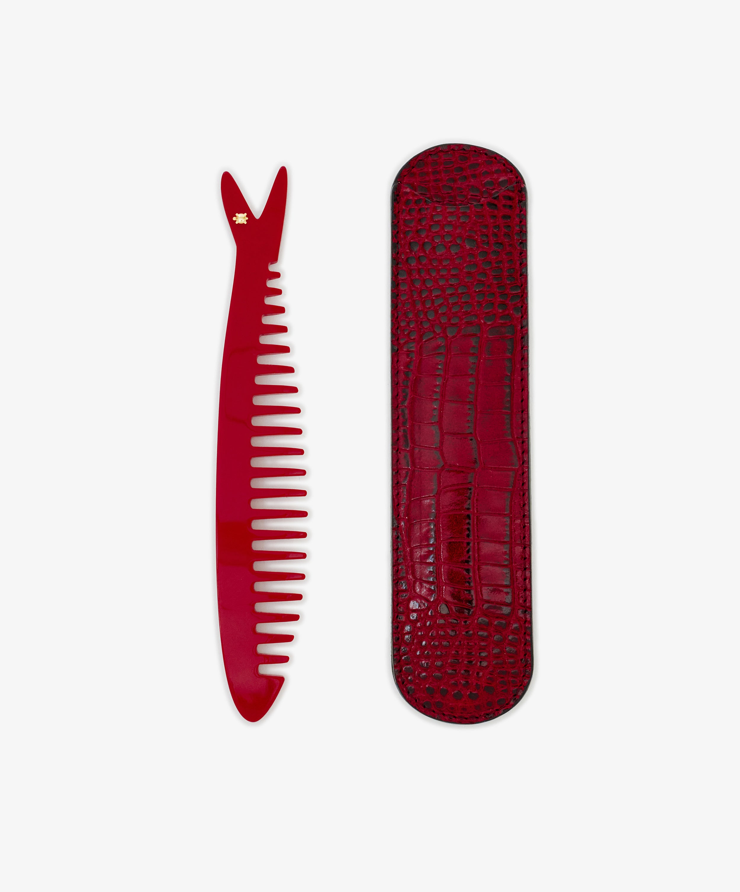 The Capri Sardine Comb, featuring a small star near the top, is placed beside a textured red case on a white background.