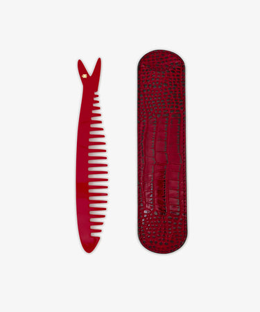 The Capri Sardine Comb, featuring a small star near the top, is placed beside a textured red case on a white background.