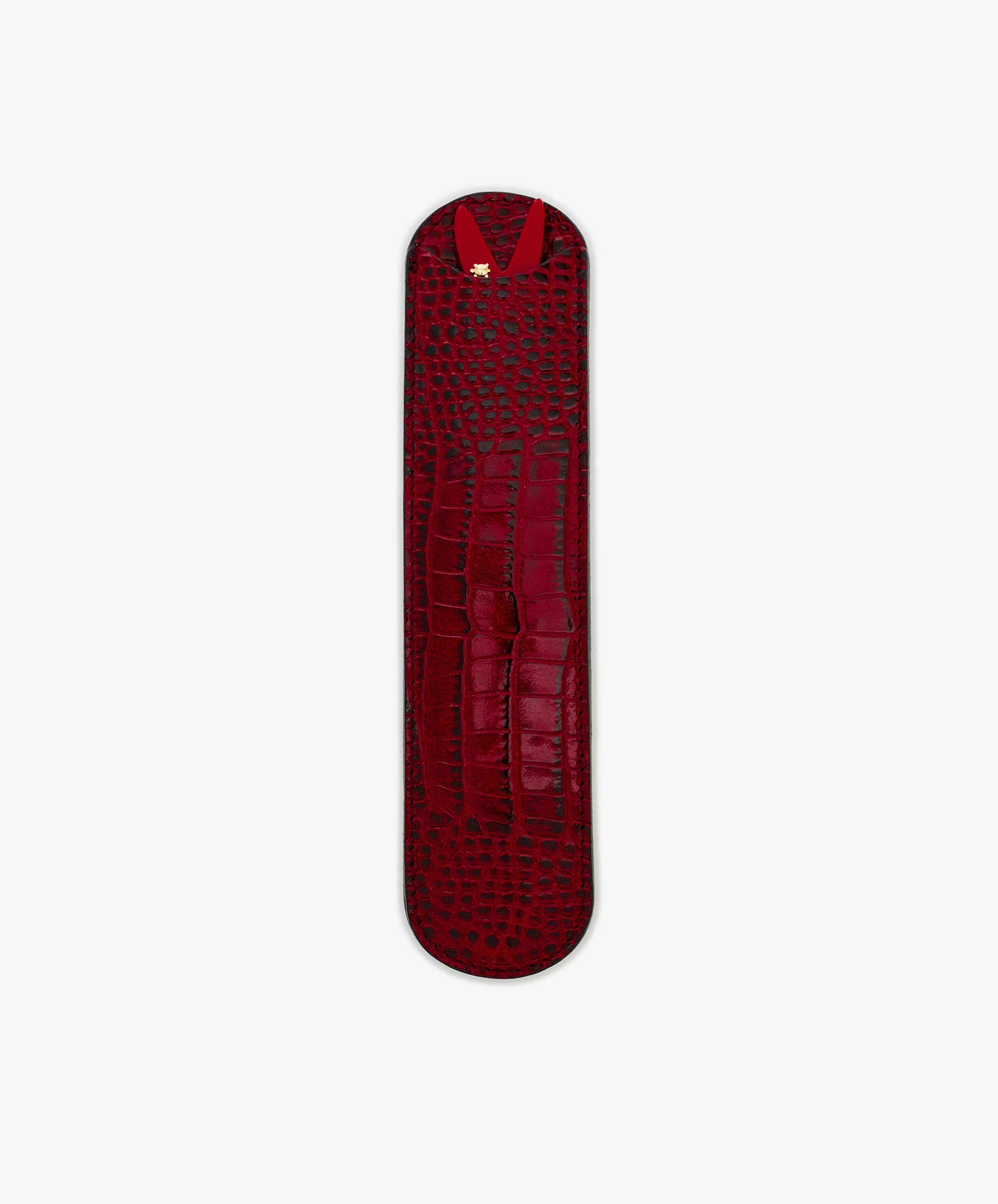 The Capri Sardine Comb is shown on a plain white background in a sleek, narrow red leather crocodile-textured case with rounded ends and a gold accent, perfect for storing your favorite tortoiseshell comb.