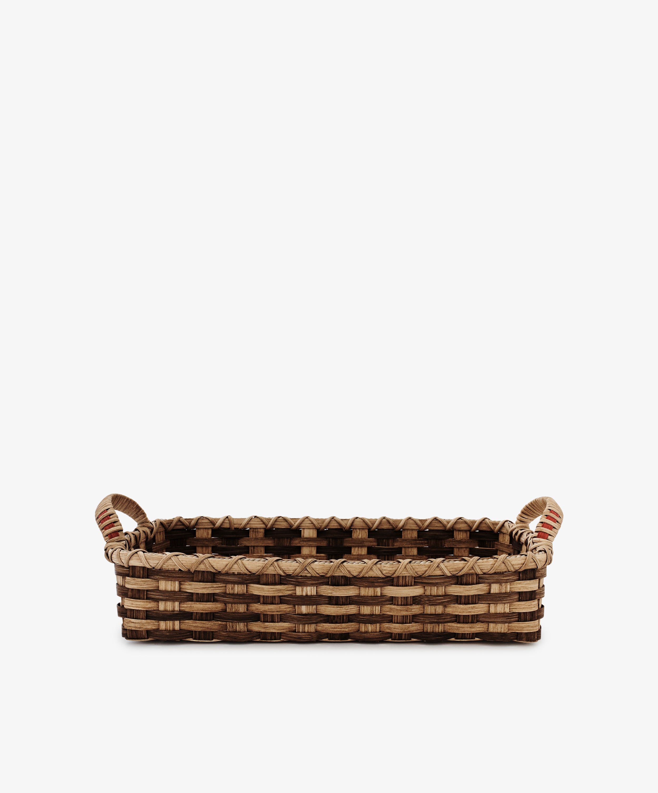 The Folk Fleur Breakfast Tray features a rectangular woven reed design in light and dark brown, two handles, and a patterned rim. Presented on a white background.