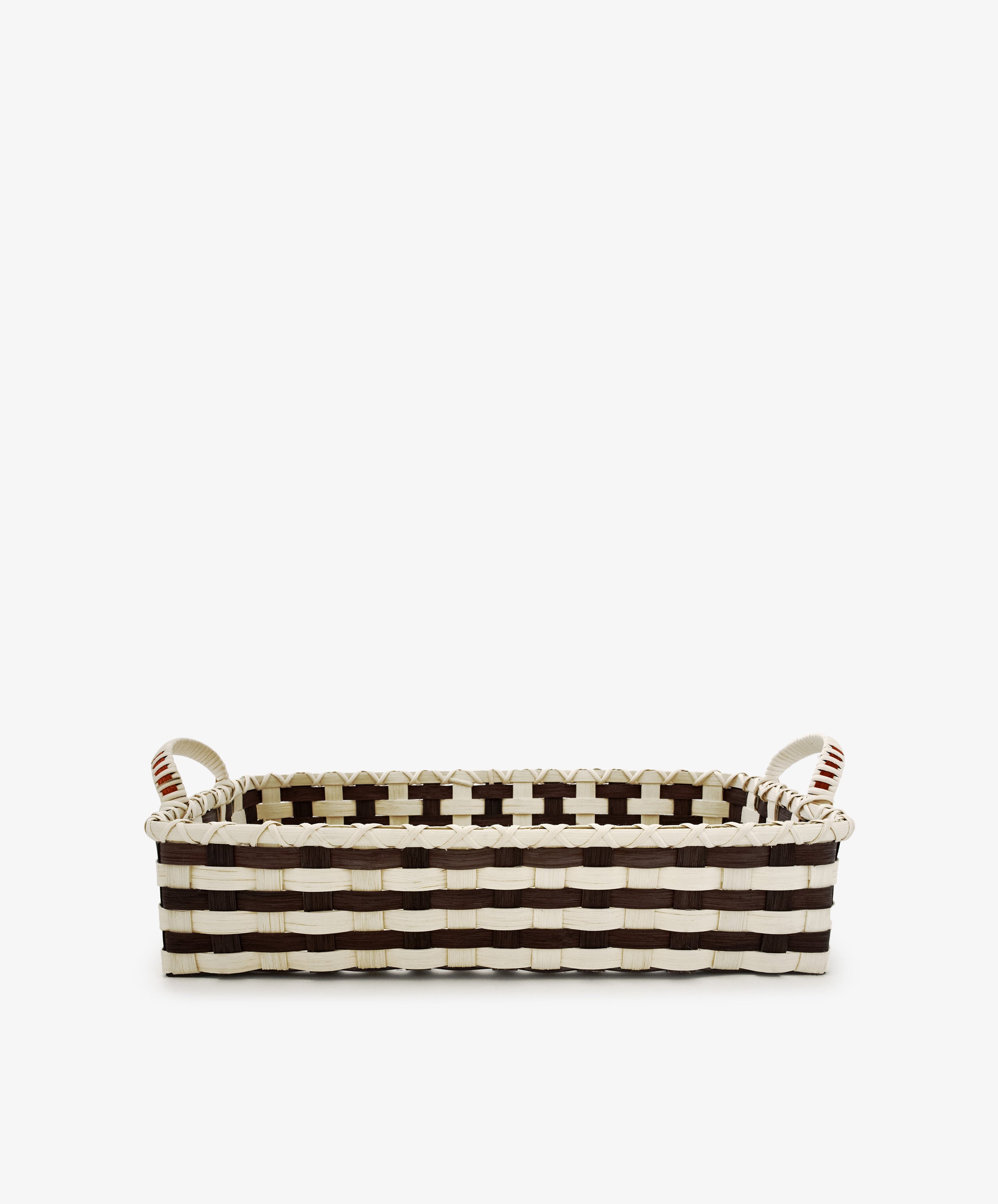 The Folk Fleur Breakfast Tray, featuring a black and white woven pattern and two sturdy handles, is handwoven to capture rustic basketware charm while combining style with everyday practicality. Photographed on a plain white background, this rectangular basket makes an elegant and functional addition to your home.