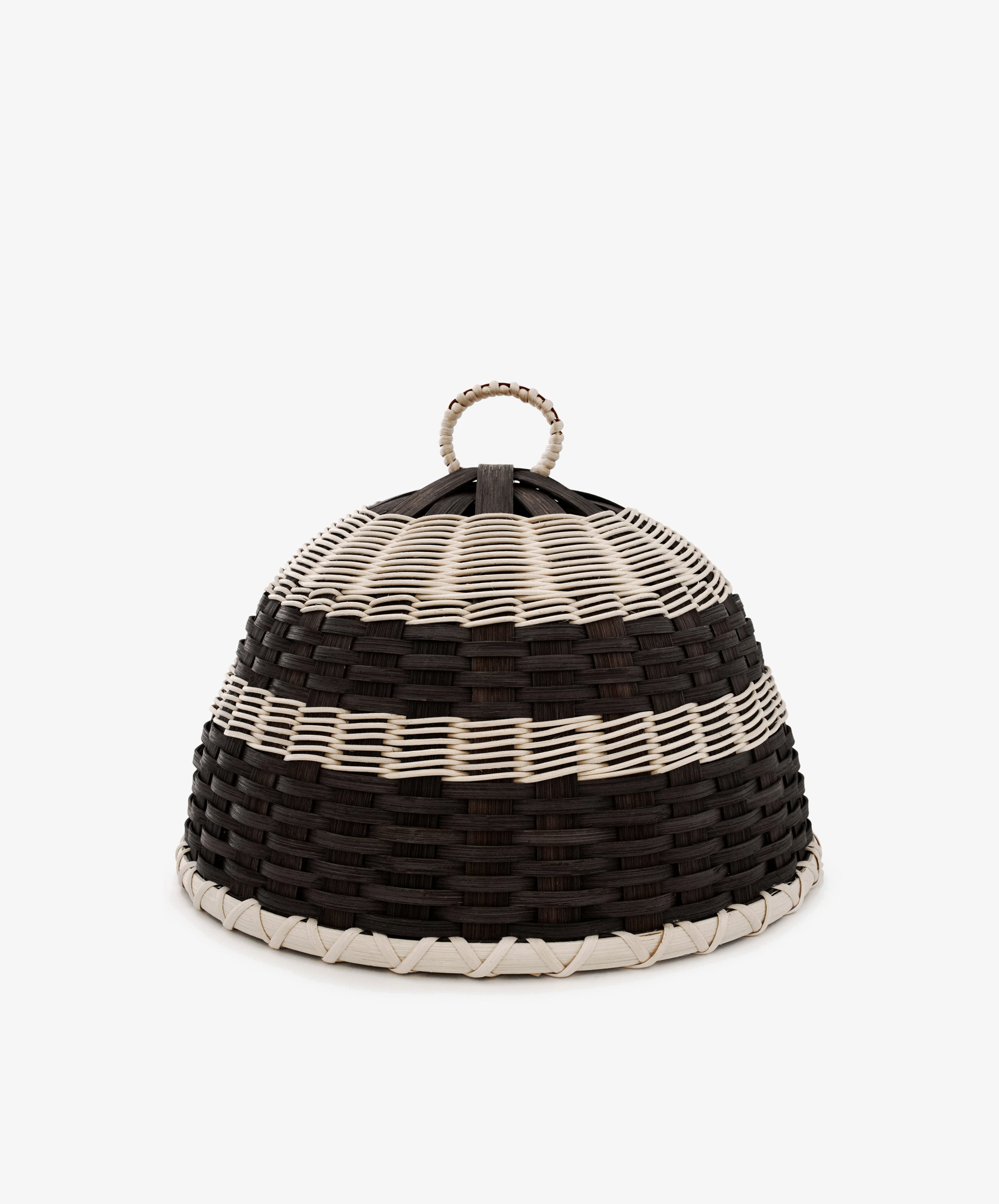 The Folk Fleur Cloche is a dome-shaped, handwoven basket featuring black, white, and brown horizontal stripes and a loop handle on top. Perfect as a stylish cheese cover for outdoor entertaining, it is set against a plain background.