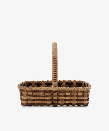 The Folk Fleur Hand Basket, a rectangular rattan basket with an upright handle crafted from natural materials, is displayed against a plain white background.