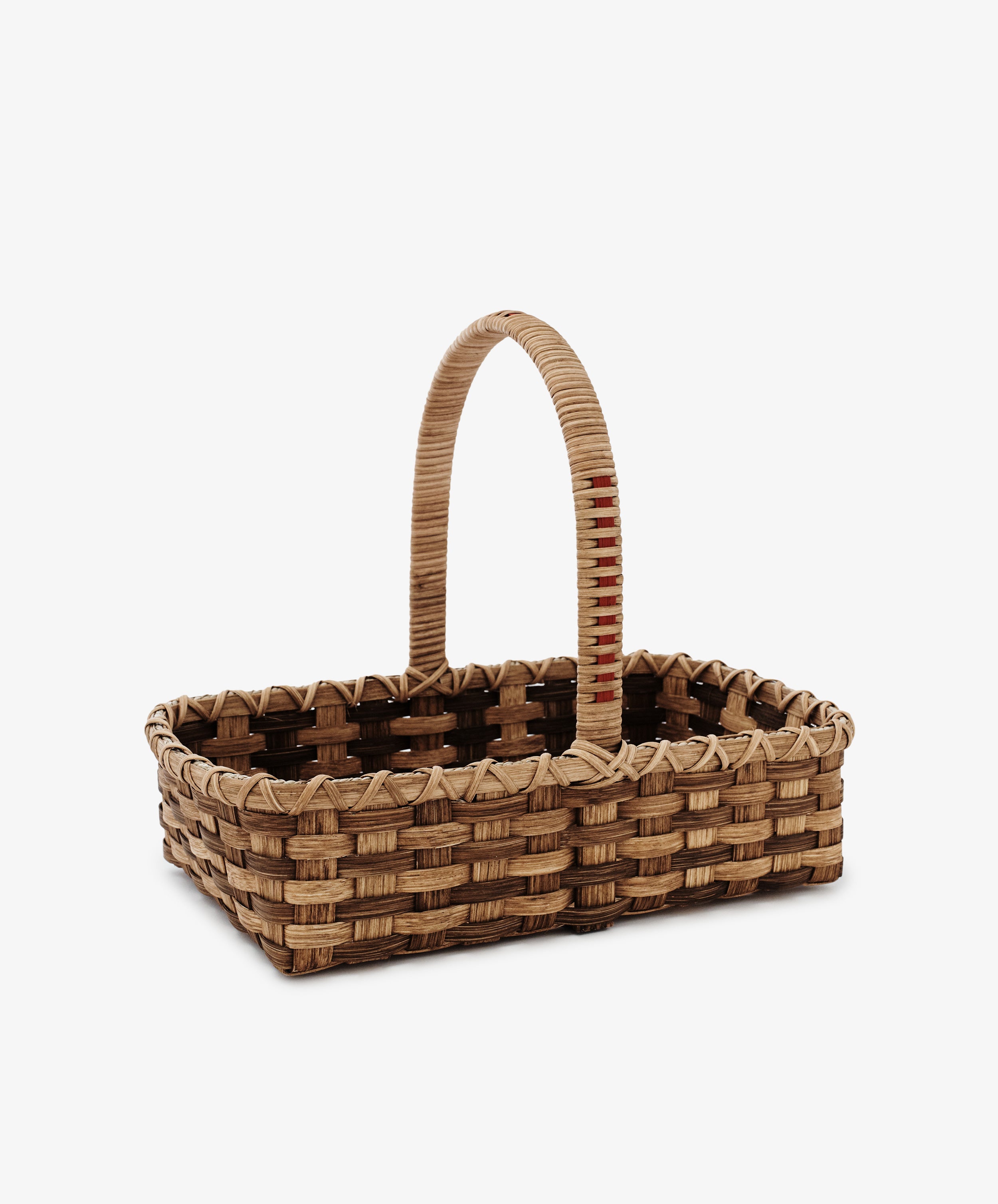The Folk Fleur Hand Basket is a rectangular rattan basket with a single arched handle, crafted from natural materials and shown on a plain white background.