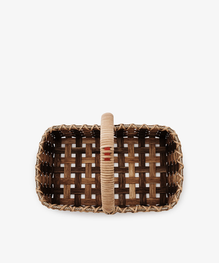 The Folk Fleur Hand Basket is a rectangular woven rattan basket with a central handle, crafted from natural materials and shown against a plain white background.