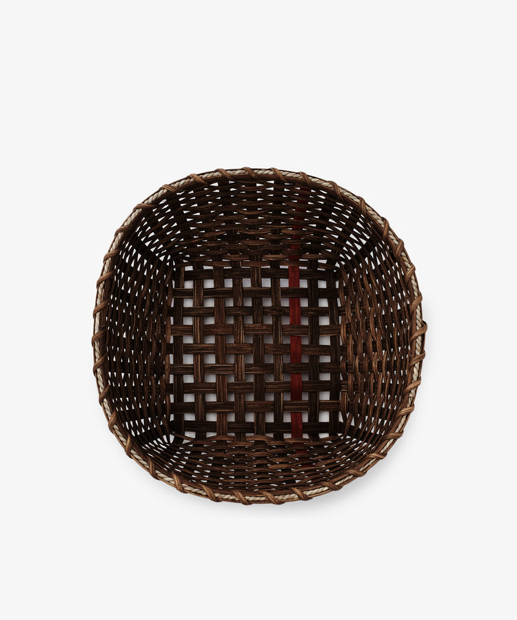 The Medium Love Basket is a square, handwoven basket with an open top and a grid pattern, featuring a striking vertical dark red-brown strip—ideal as a decorative kitchen accent.