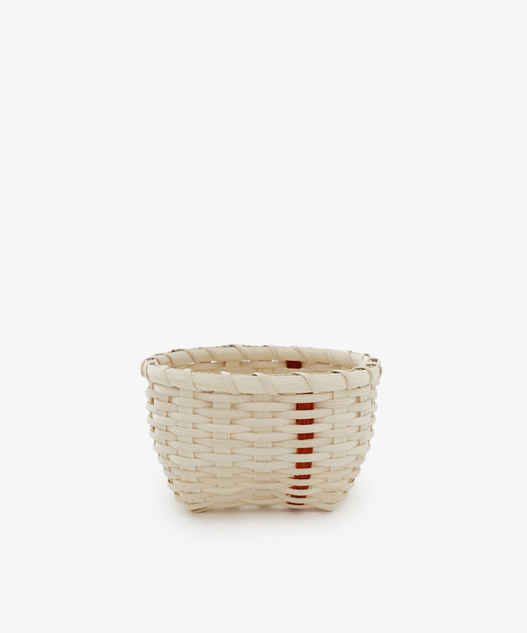 The Little Love Basket is a small handwoven basket in natural beige with a single vertical red stripe, shown on a plain white background.