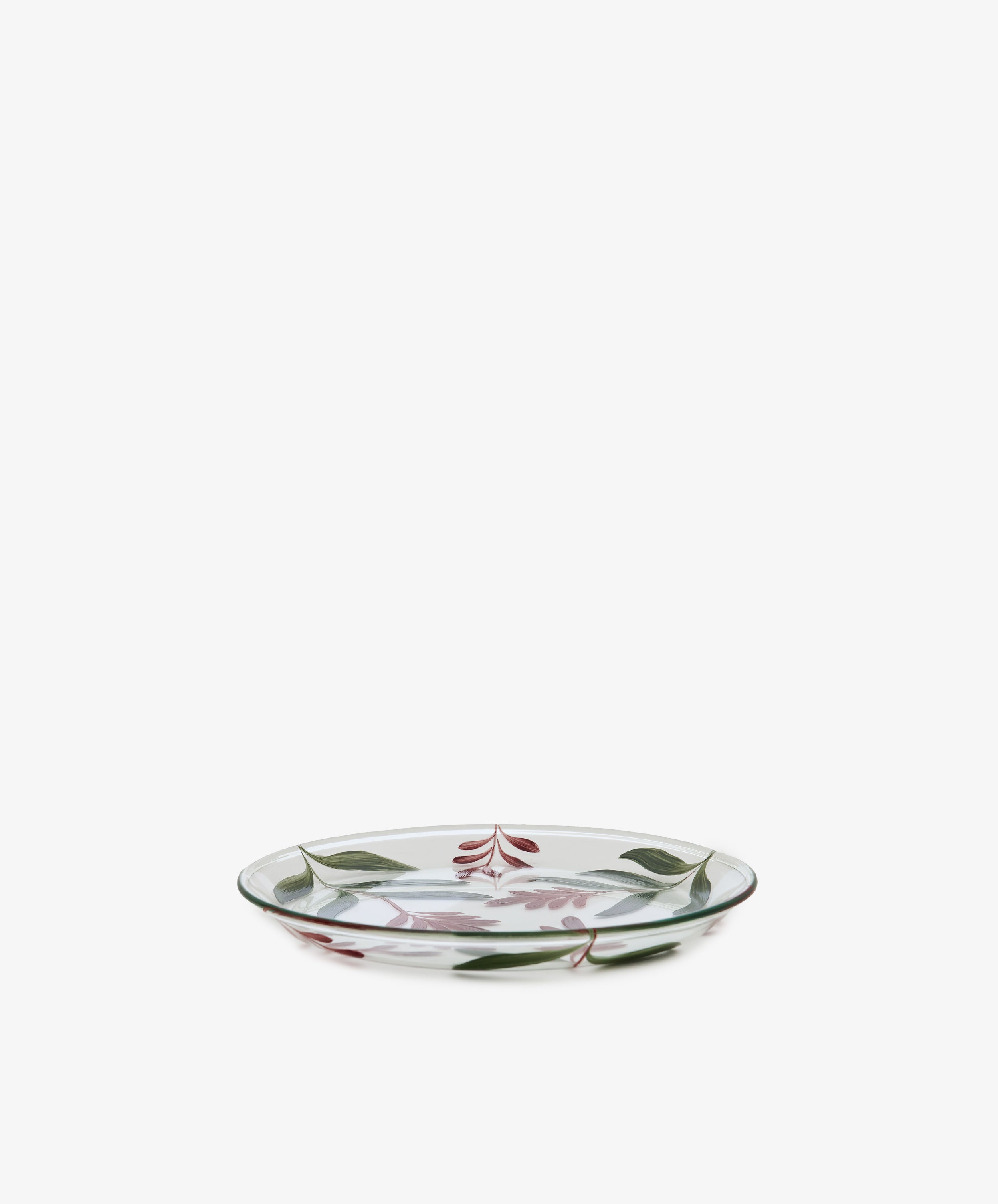 The Botanical Little Plate, a clear glass plate adorned with a hand-painted green and red floral and leaf design, serves as an eye-catching dish displayed against a plain white background.