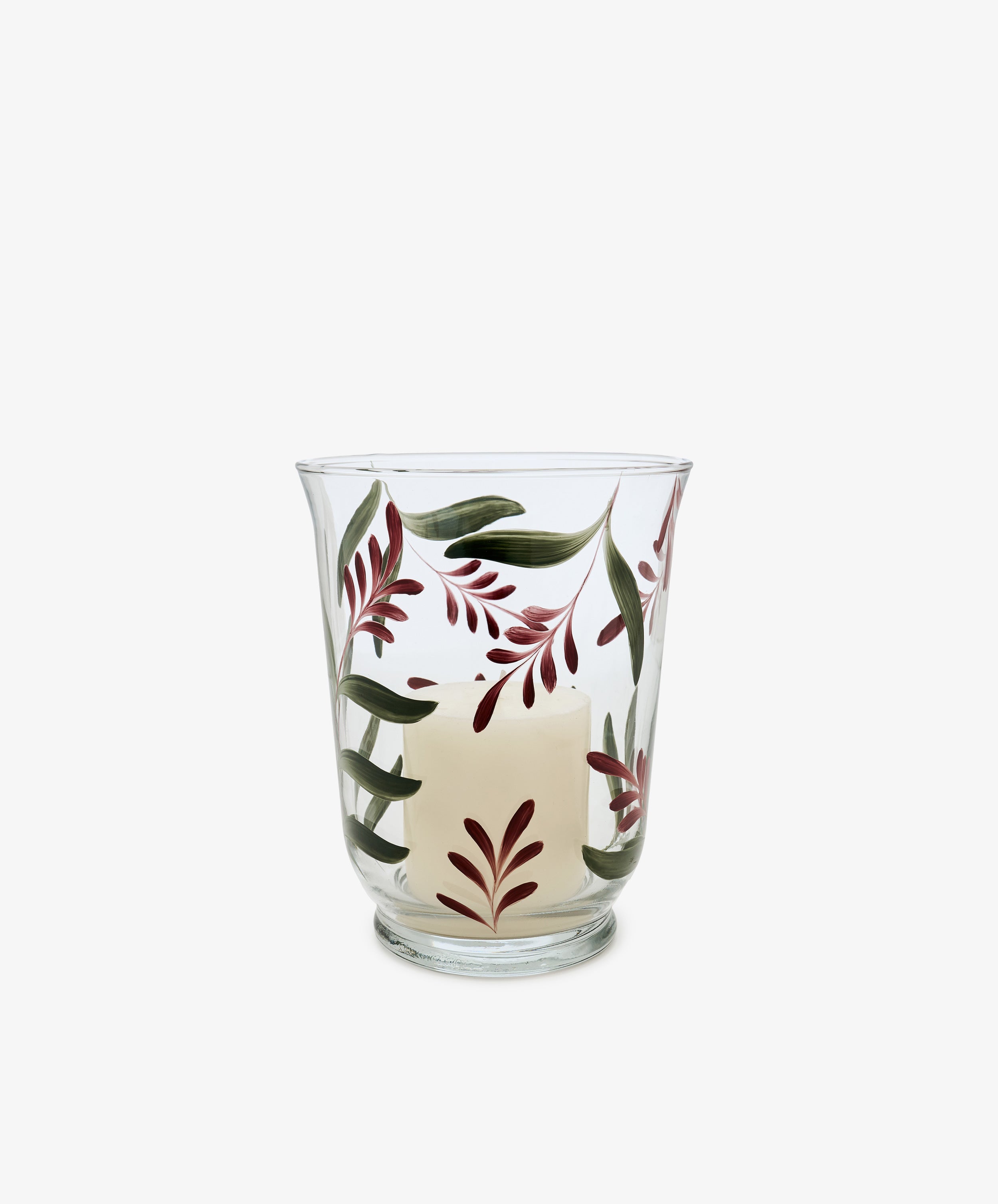 The Botanical Candle Holder features clear glass and a partially melted white candle, adorned with green and burgundy leaves, making it a charming decorative table centerpiece.