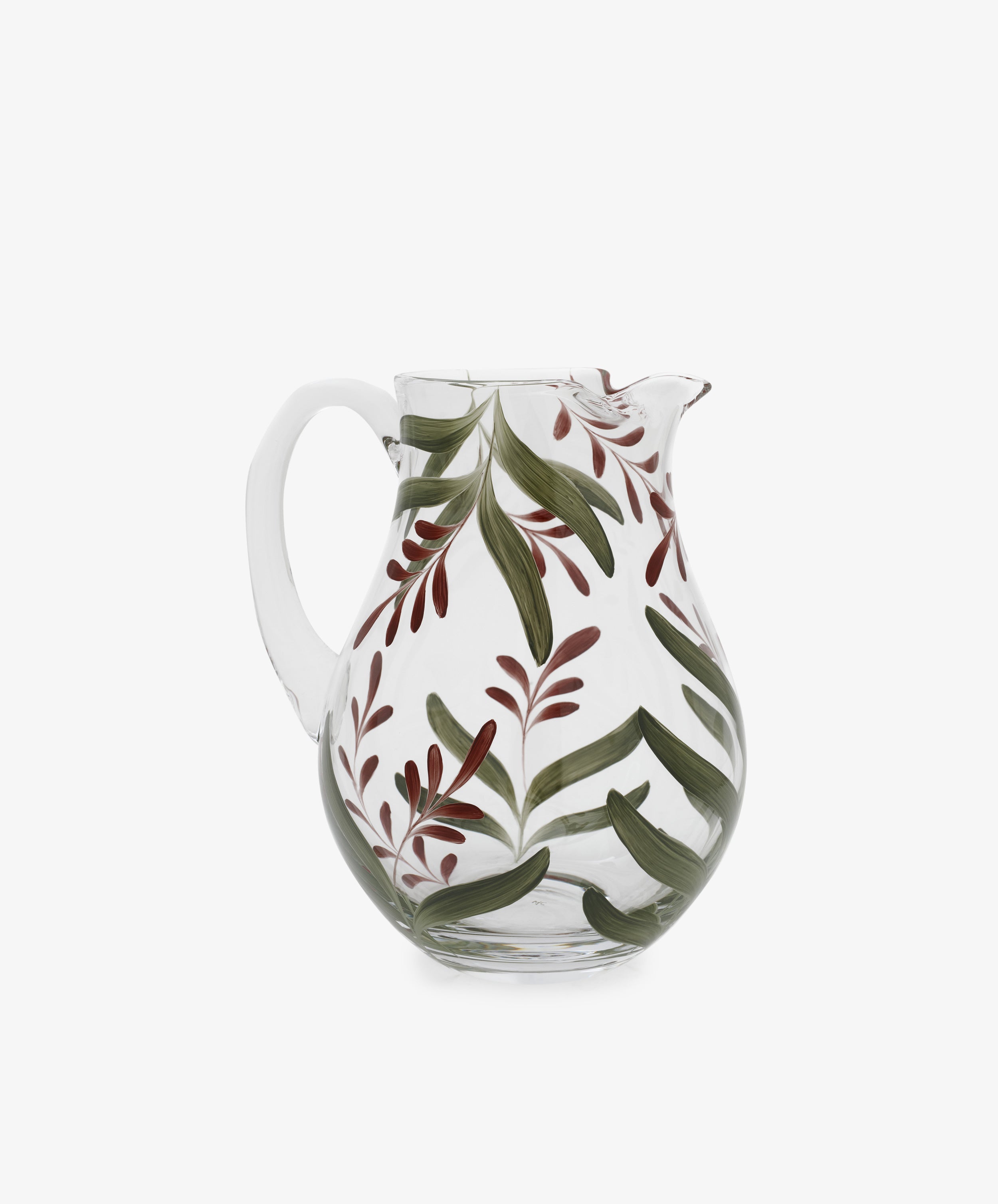 The Botanical Jug is a clear glass pitcher with a handle, featuring green and red leaf designs that evoke hand-painted craftsmanship—ideal for bringing a handmade touch to your table.