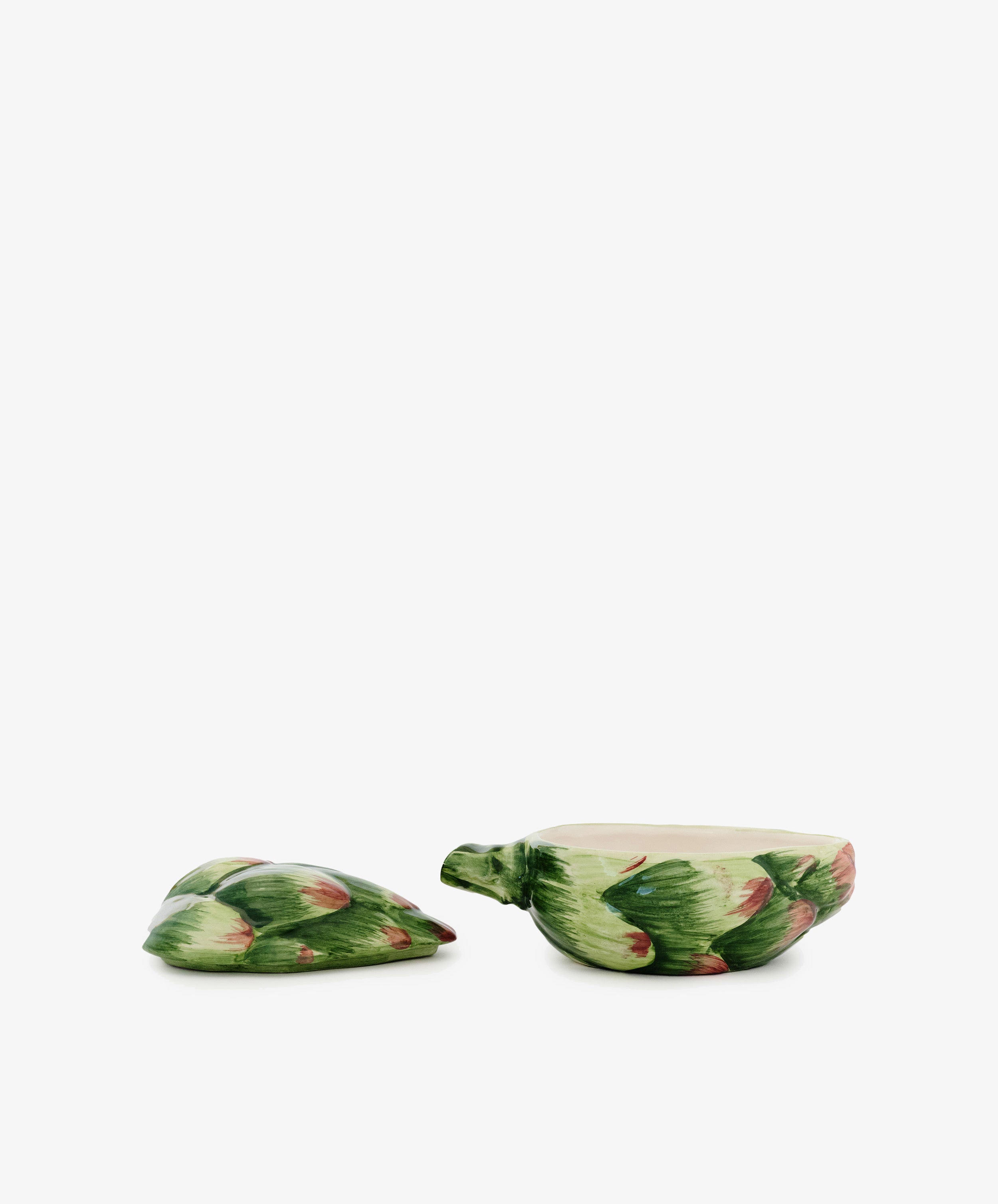 The Artichoke Sauce Bowl is a ceramic container shaped and painted like an artichoke, perfect for adding a unique touch to Italian kitchen tableware. Displayed with its lid off and set beside the base on a white background.