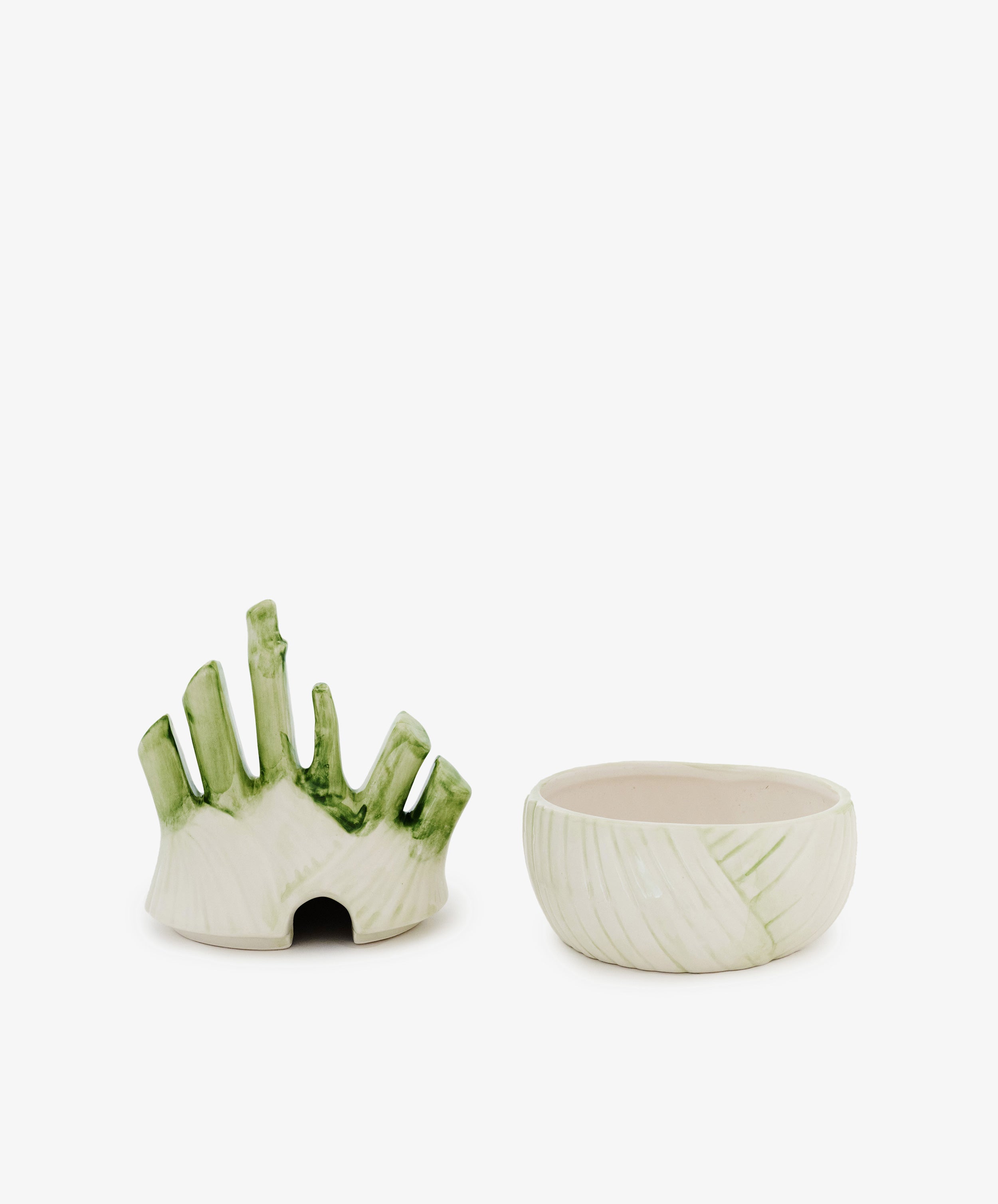The Fennel Sauce Bowl sits beside another ceramic serving piece with upright, finger-like shapes, green accents, and a small base opening—evoking designs by Italian ceramicists.
