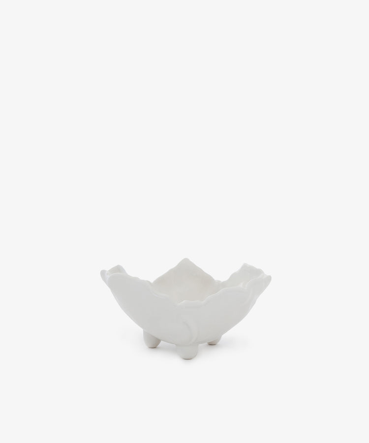 The Leaf Bowl is a white ceramic dish with a wavy, flower-like edge and three small rounded feet, shown on a plain white background. It's a charming piece perfect for display.