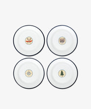 The Camp Plates, Set of 4, features white enamel with black rims and playful illustrations—crossed paddles, bear face, compass, and pine tree—for a vintage scout badge touch to kids’ tableware.