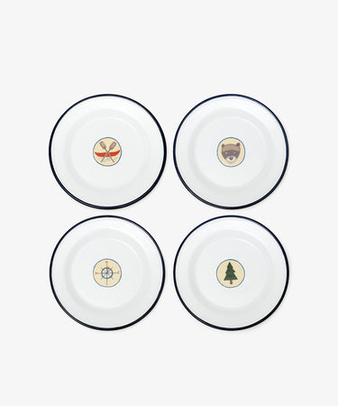 The Camp Plates, Set of 4, features white enamel with black rims and playful illustrations—crossed paddles, bear face, compass, and pine tree—for a vintage scout badge touch to kids’ tableware.