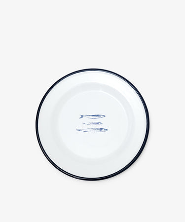 The Il Pesce Enamel Plate, Set of 2, features a white plate with a blue rim and an illustration of three blue sardines in the center, shown against a plain white background.