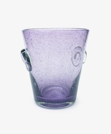 The Lauren Champagne Bucket is a transparent purple glass bucket with two side handles, a translucent surface, and embedded air bubbles, shown on a white background.