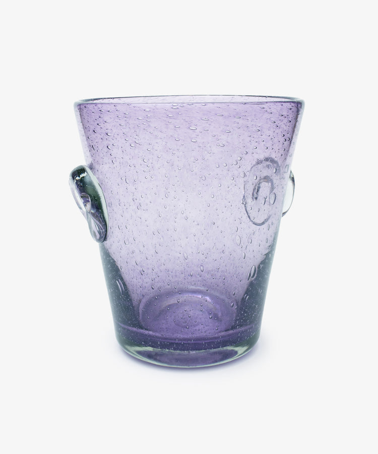 The Lauren Champagne Bucket is a transparent purple glass bucket with two side handles, a translucent surface, and embedded air bubbles, shown on a white background.