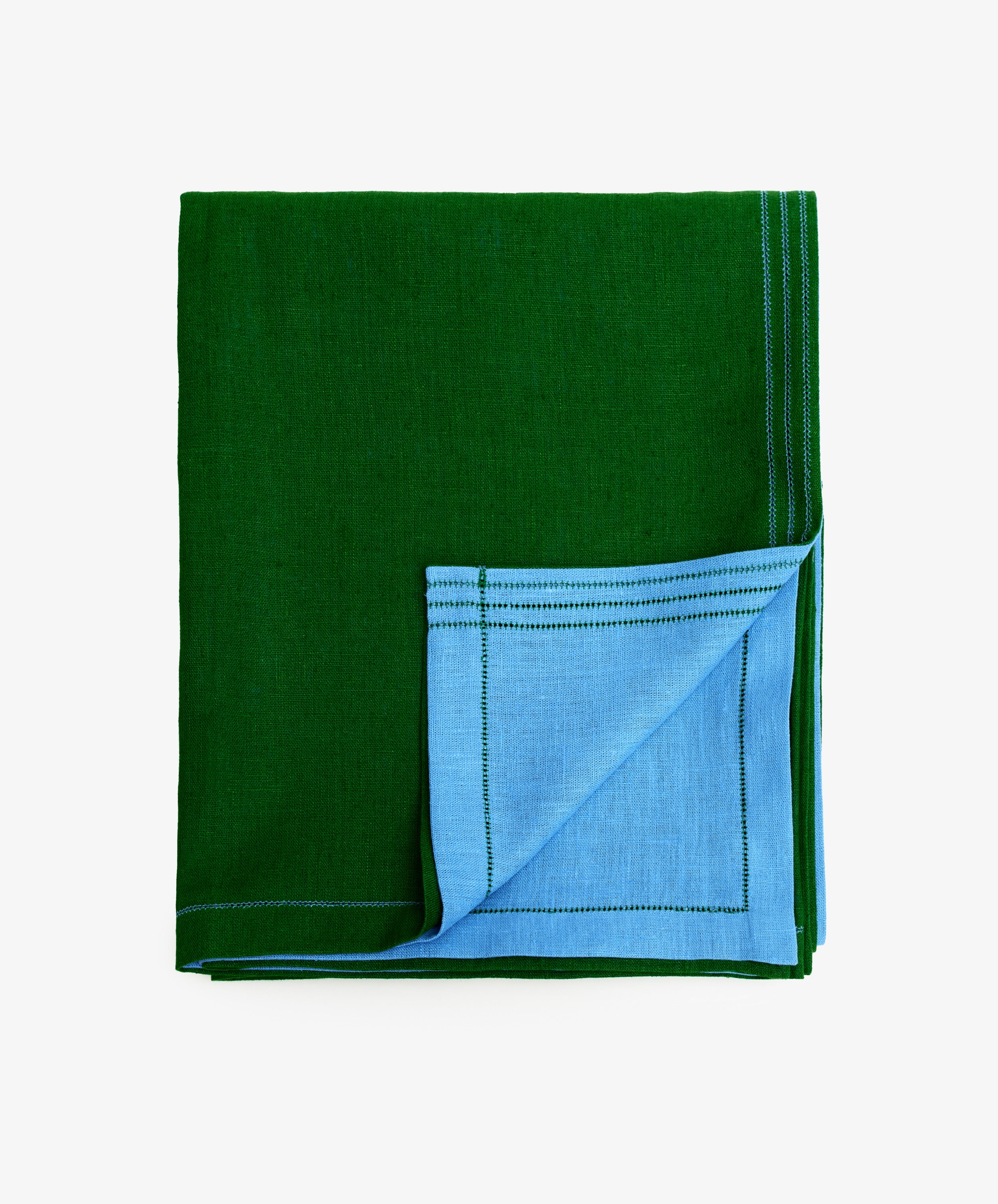 Magnetic Color Field Tablecloth. Folded green linen cloth with blue stitching, with bottom corner flipped up to show blue side.