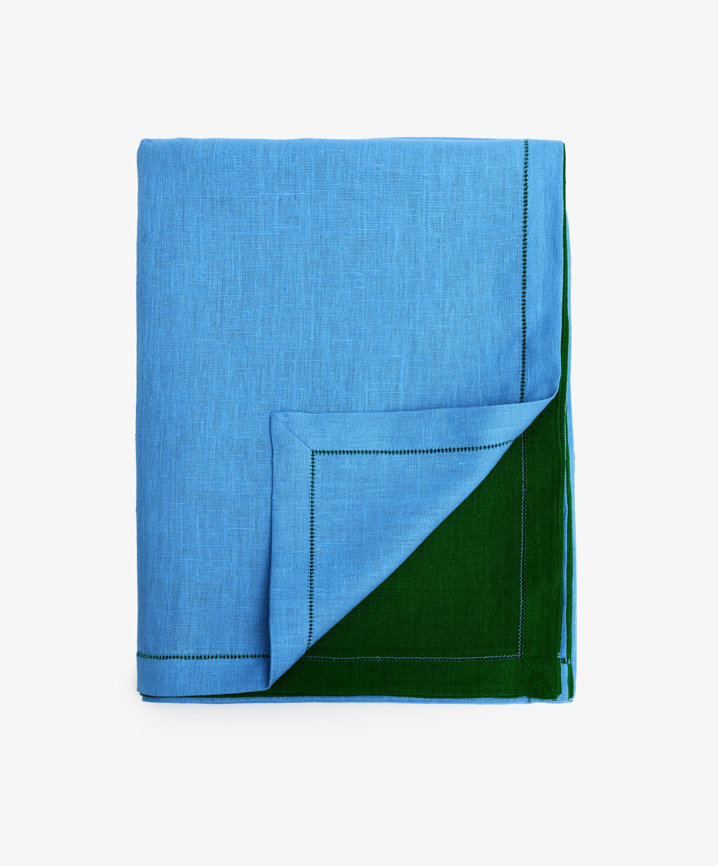 Magnetic Color Field Tablecloth. Folded blue linen cloth with green stitching, with bottom corner flipped up to show green side.