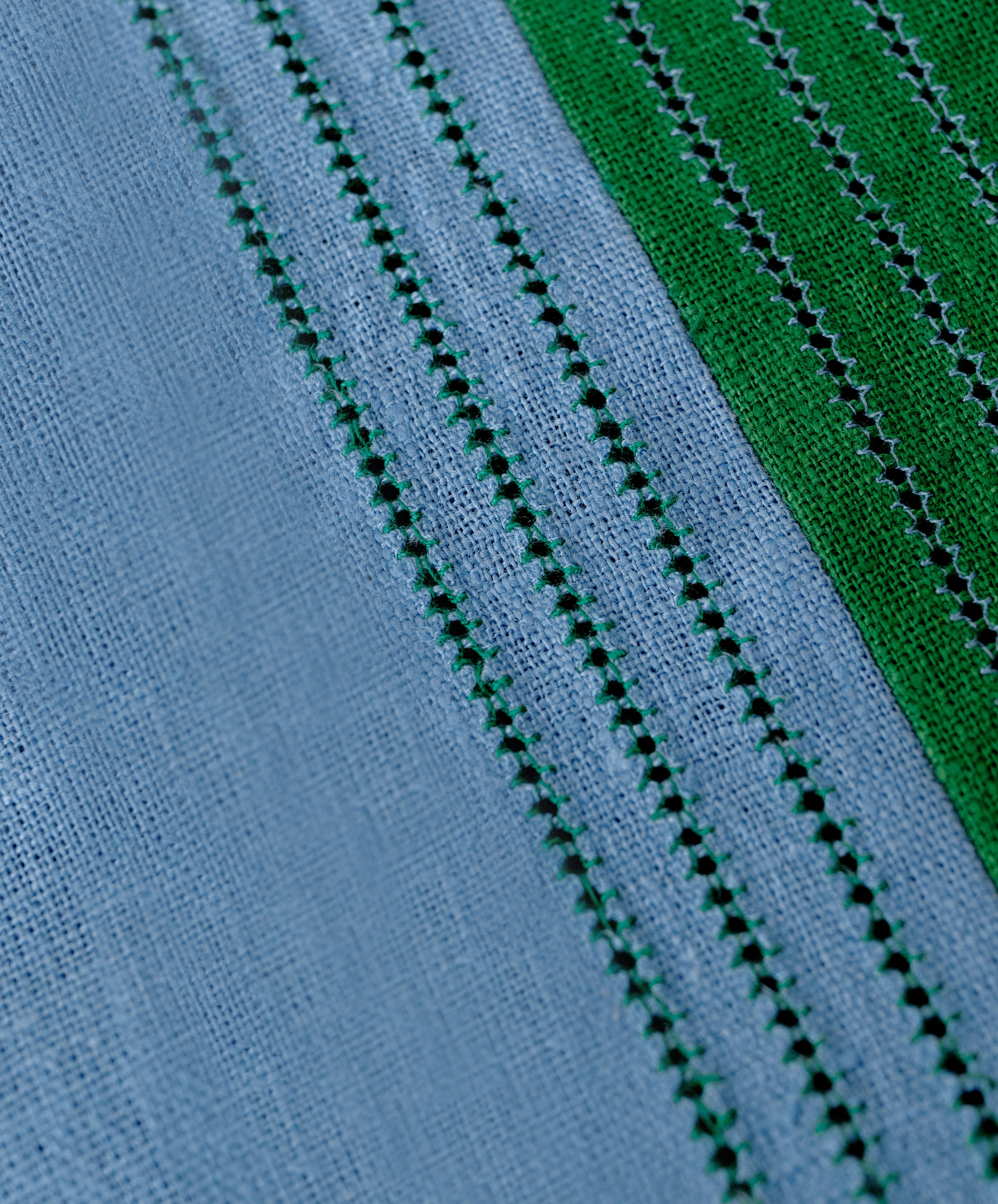 Close-up of Magnetic Color Field Tablecloth, in blue and green linen with stitching.